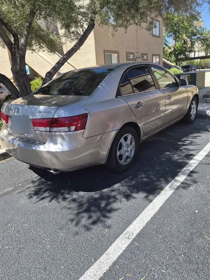 Gold Hyundai Sonata sedan bought by Cash For Cars Nevada, rear view in a parking lot, license plate blurred