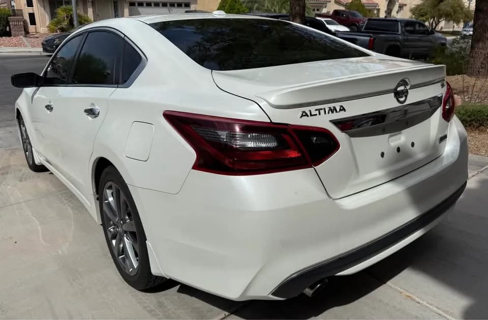 Pearl white Nissan Altima SR sedan bought by Cash For Cars Nevada, rear view in a driveway
