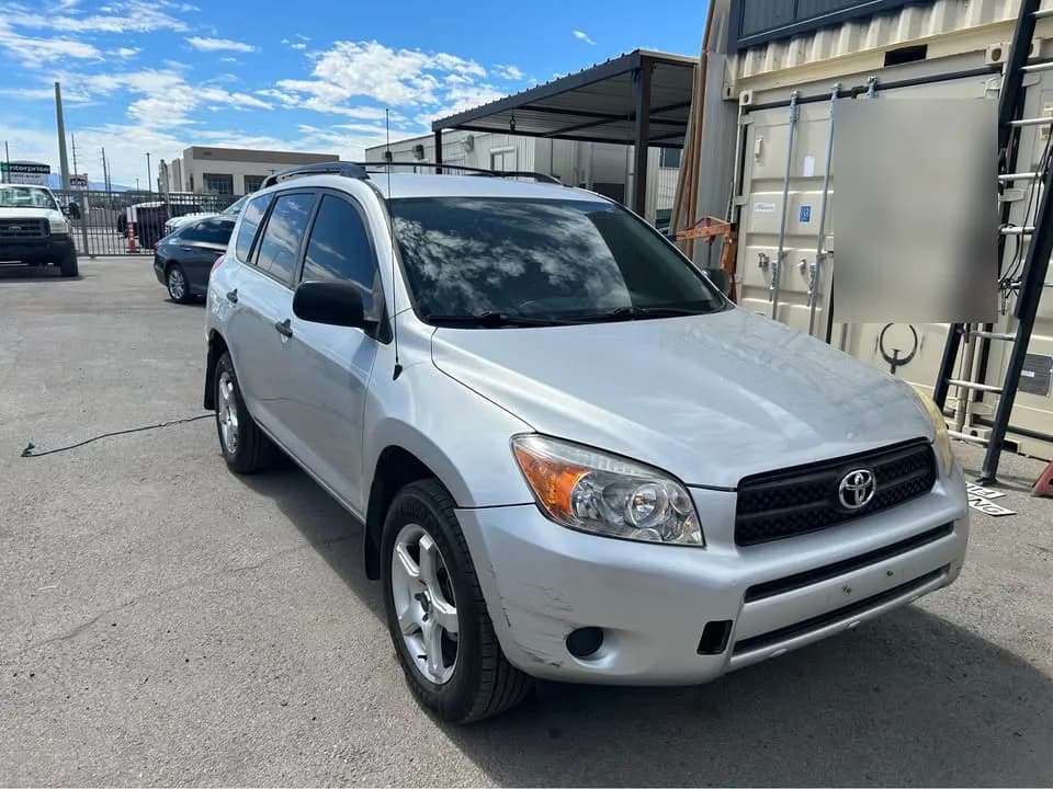 Silver Toyota RAV4 SUV bought by Cash For Cars Nevada, parked in a gravel lot next to shipping containers