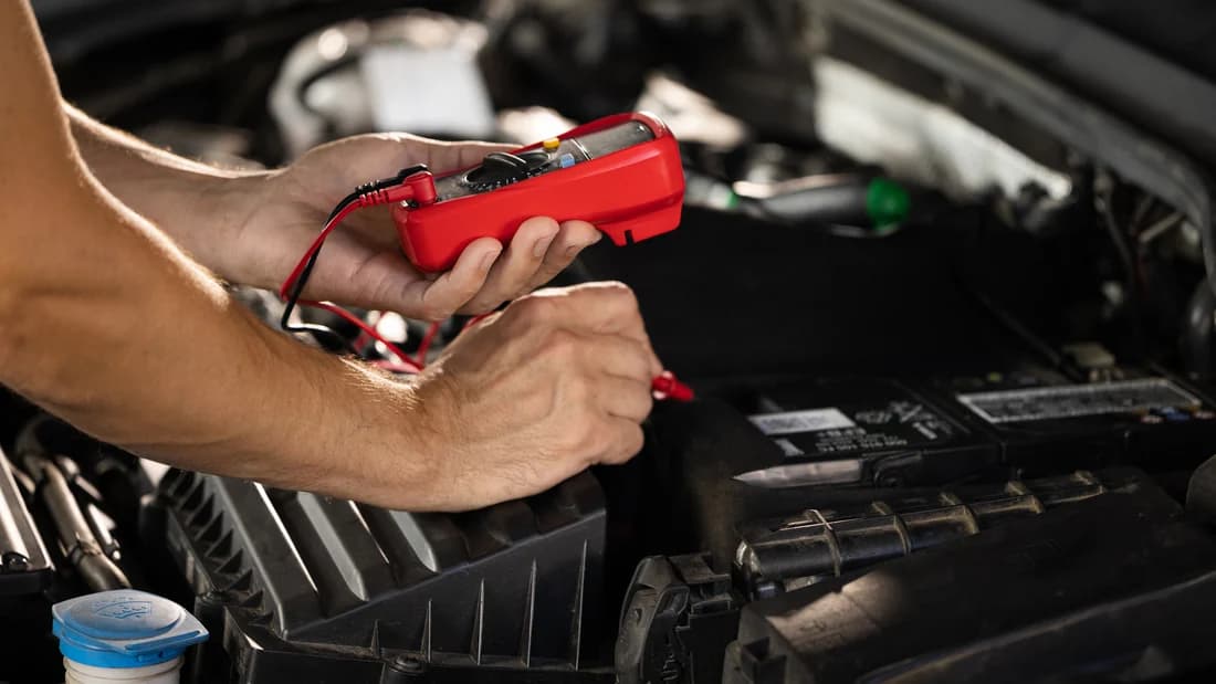 A mechanic testing a car battery with a multimeter: a car that won't start in Las Vegas may only need a battery check