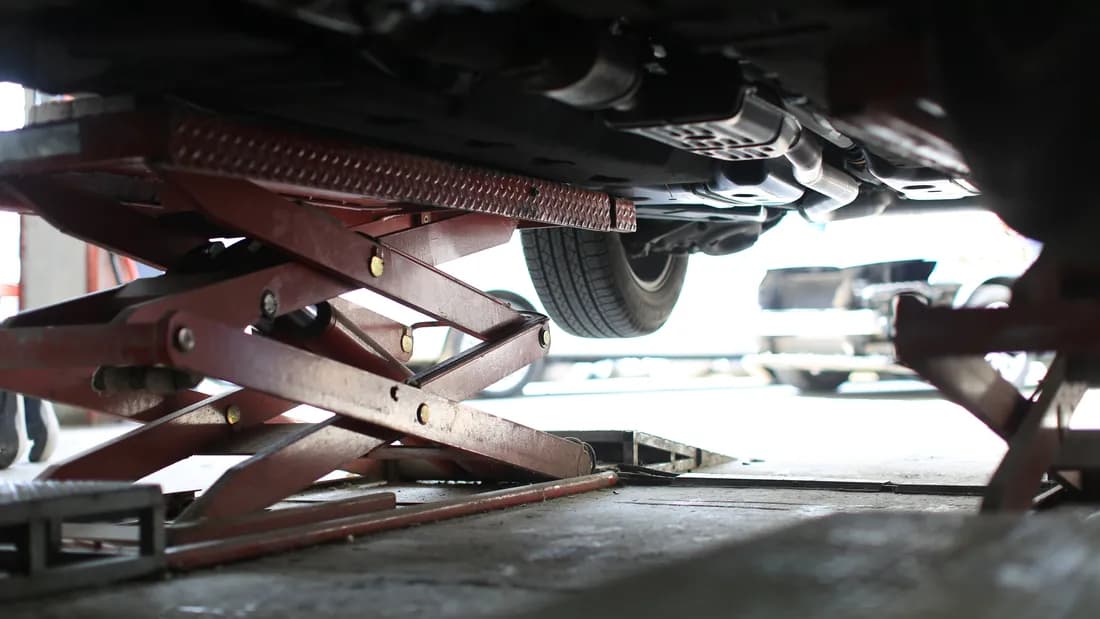 A car raised on a service lift with its underside and exhaust visible