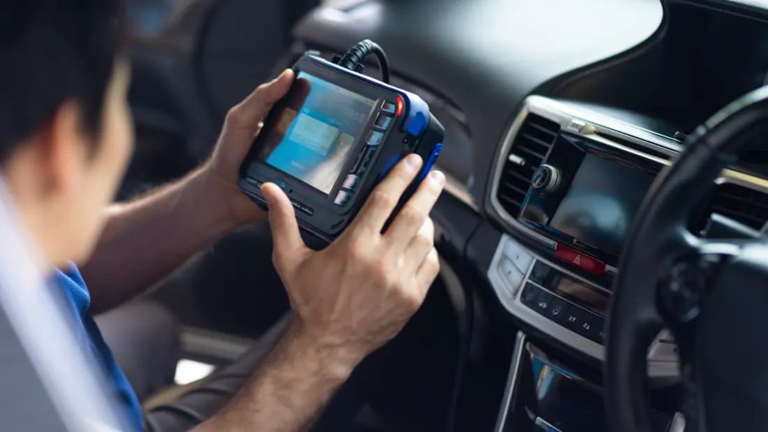 A mechanic running diagnostic software on a laptop to read a car's error codes: checking a check engine light before selling a car in Nevada
