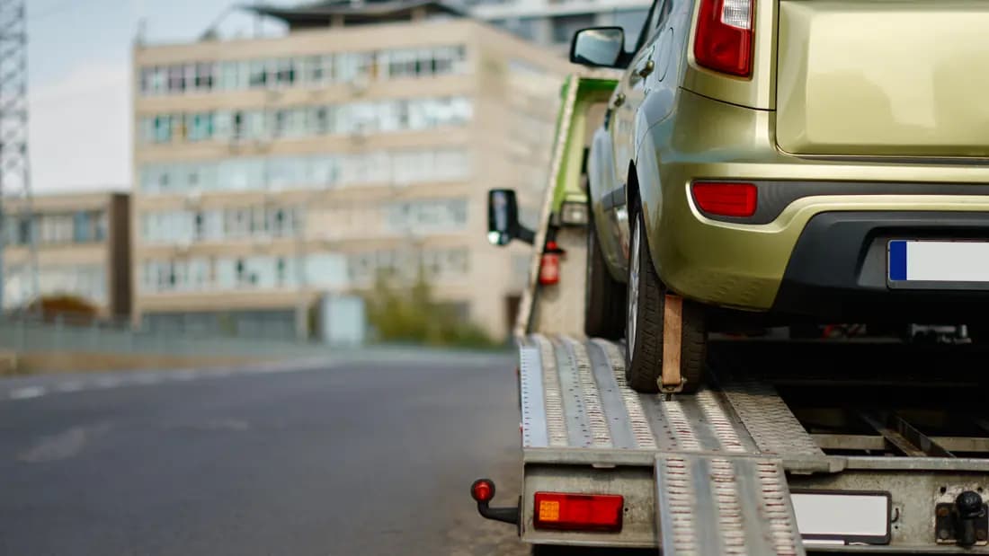 A car being winched up the ramps onto the bed of a flatbed tow truck