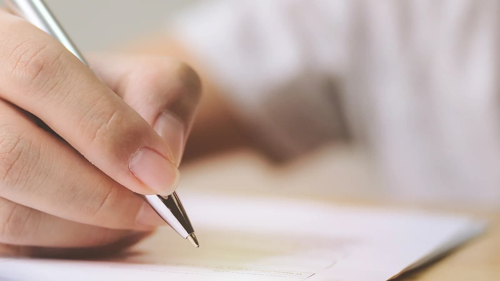 A hand holding a pen over a form: filling in the Nevada DMV bill of sale (VP-104) to sell a car privately