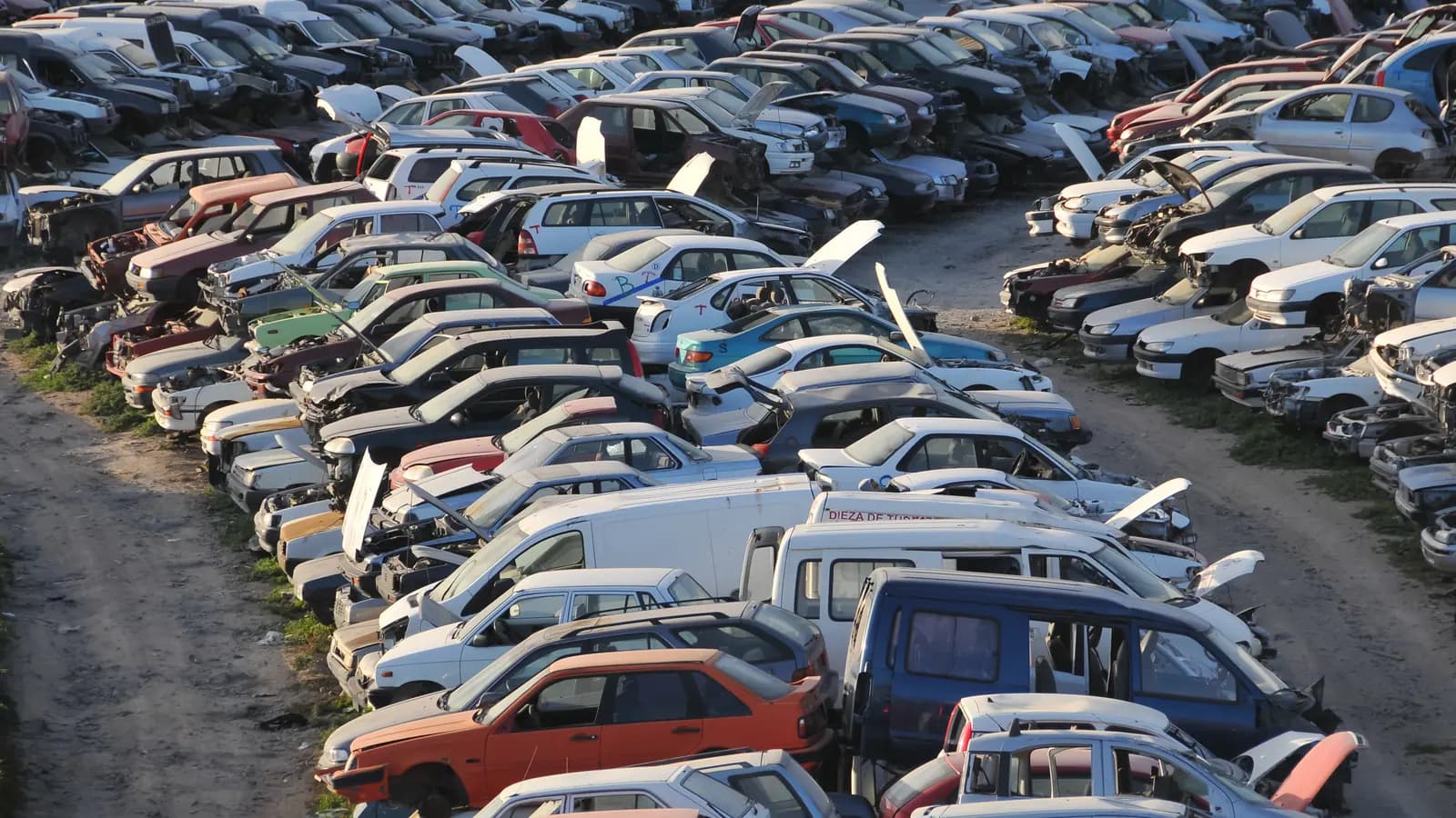 Rows of old and wrecked cars parked in a salvage yard, seen from above