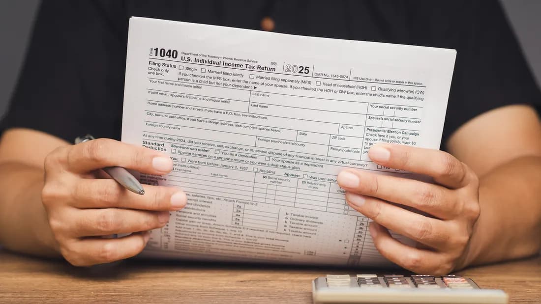 Two hands holding a U.S. individual income tax return form above a desk