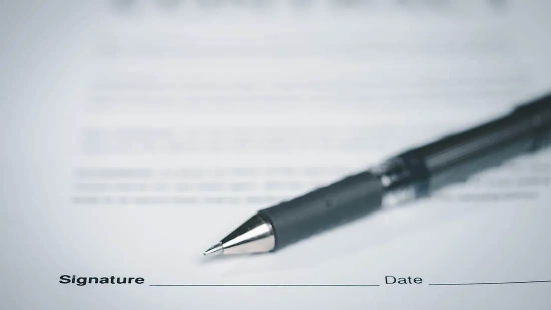A pen resting on a document's signature line: sign the title over when you junk a car in Nevada