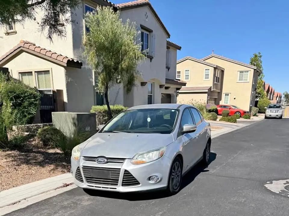 Silver 2014 Ford Focus SE sedan parked on a street of two-story homes