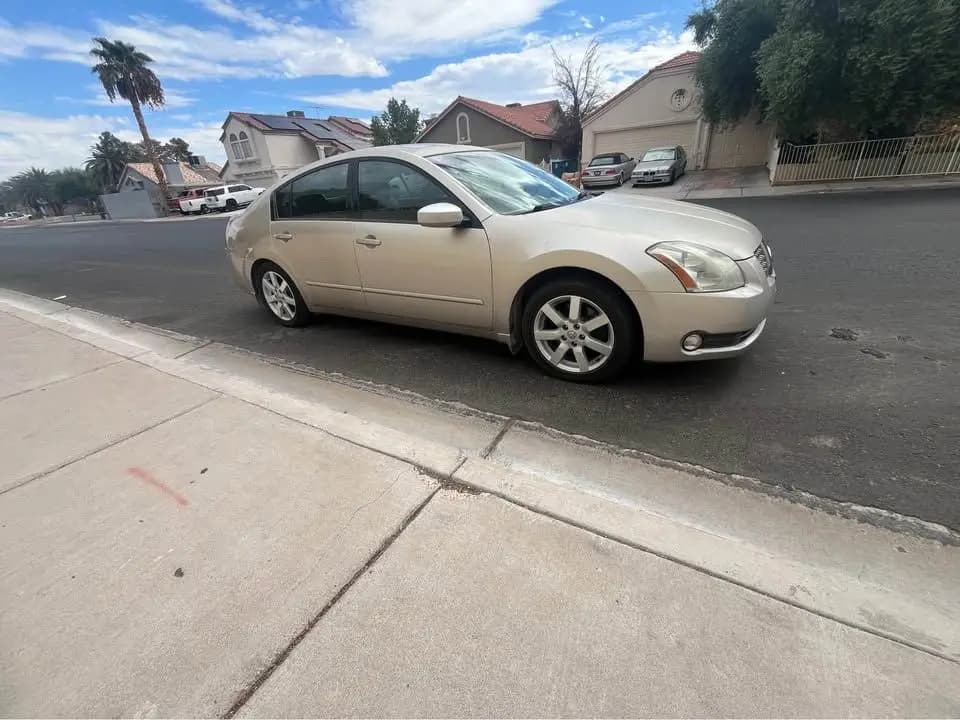 Champagne 2005 Nissan Maxima SE sedan parked at a curb in a Las Vegas neighborhood