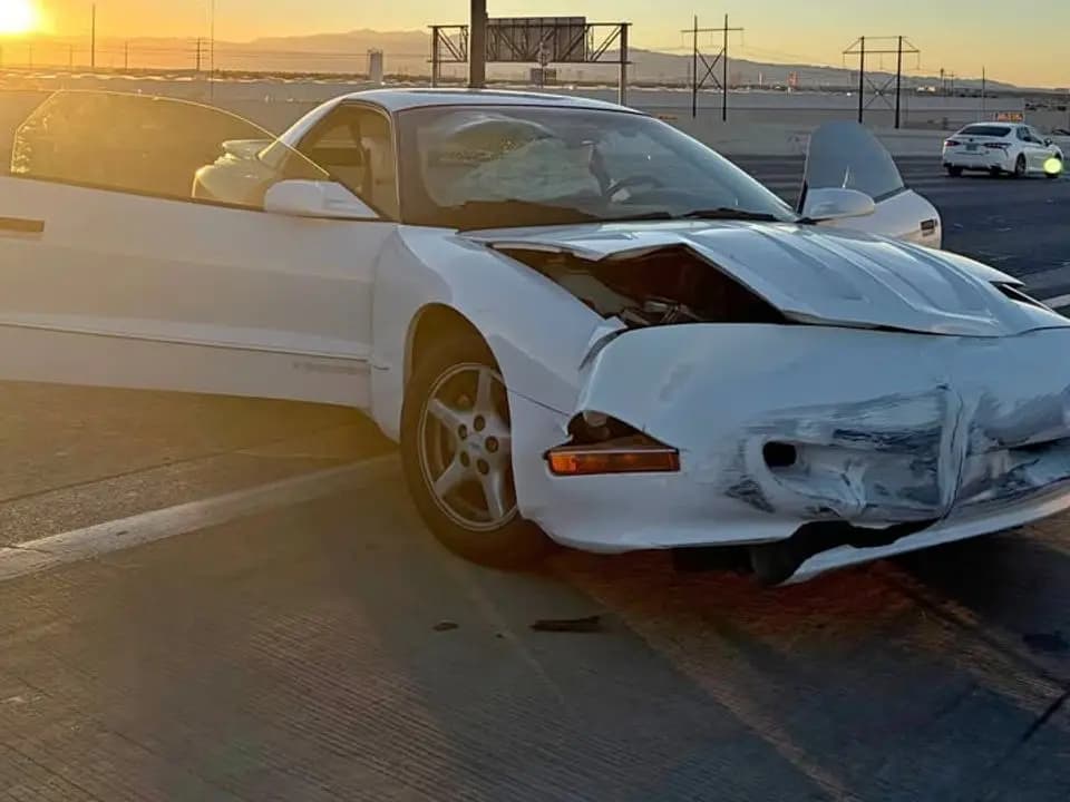 White 1997 Pontiac Firebird Trans Am with a smashed front end at sunset