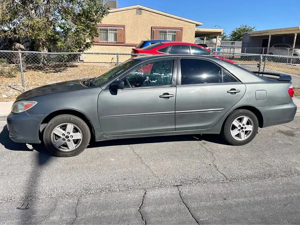 Gray 2005 Toyota Camry sedan parked beside a chain-link fence