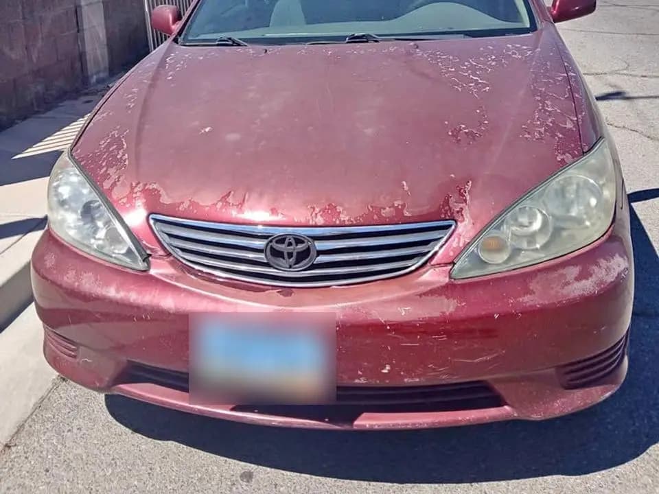 Red 2005 Toyota Camry with sun-peeled paint on the hood, license plate blurred
