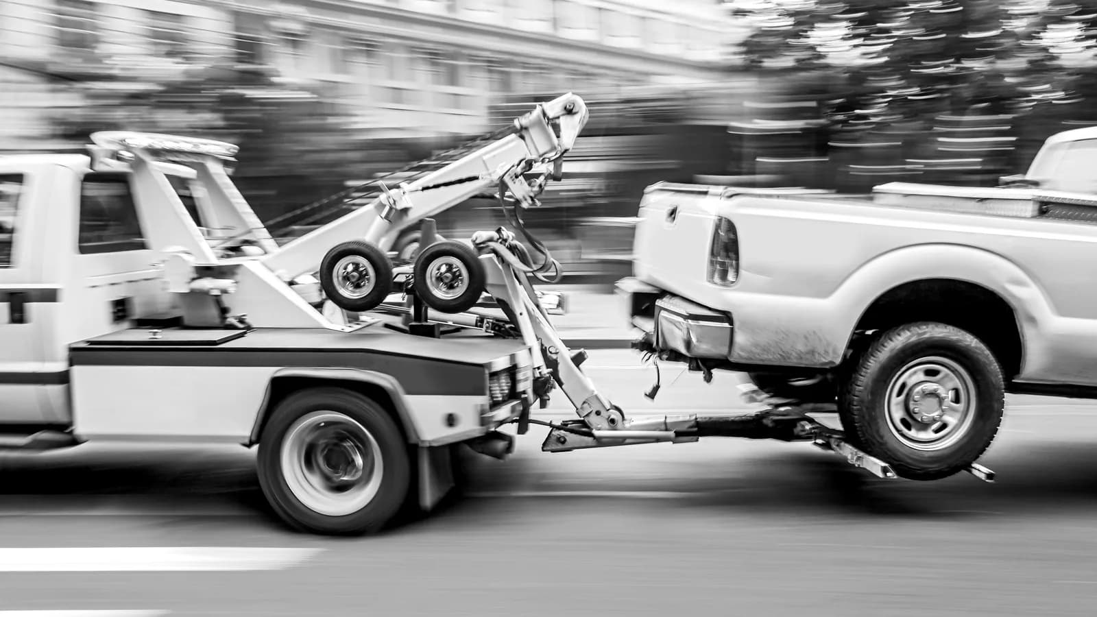 A car being towed to an impound yard A tow truck towing a pickup down a city street: what happens when your car is impounded in Las Vegas