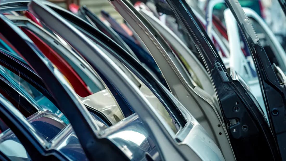 Used car doors and panels resold from salvage vehicles A tightly packed row of car doors in assorted colours standing on end at a salvage yard
