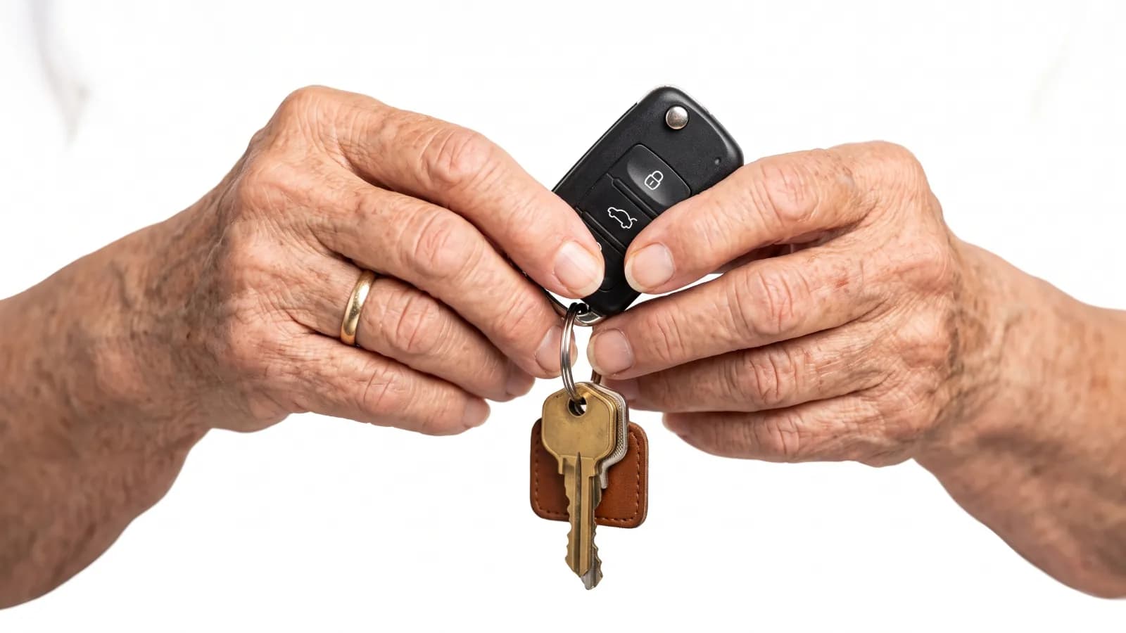 Selling a late parent’s car in Nevada with the DMV’s transfer forms An older person’s hands holding a car key fob and a house key