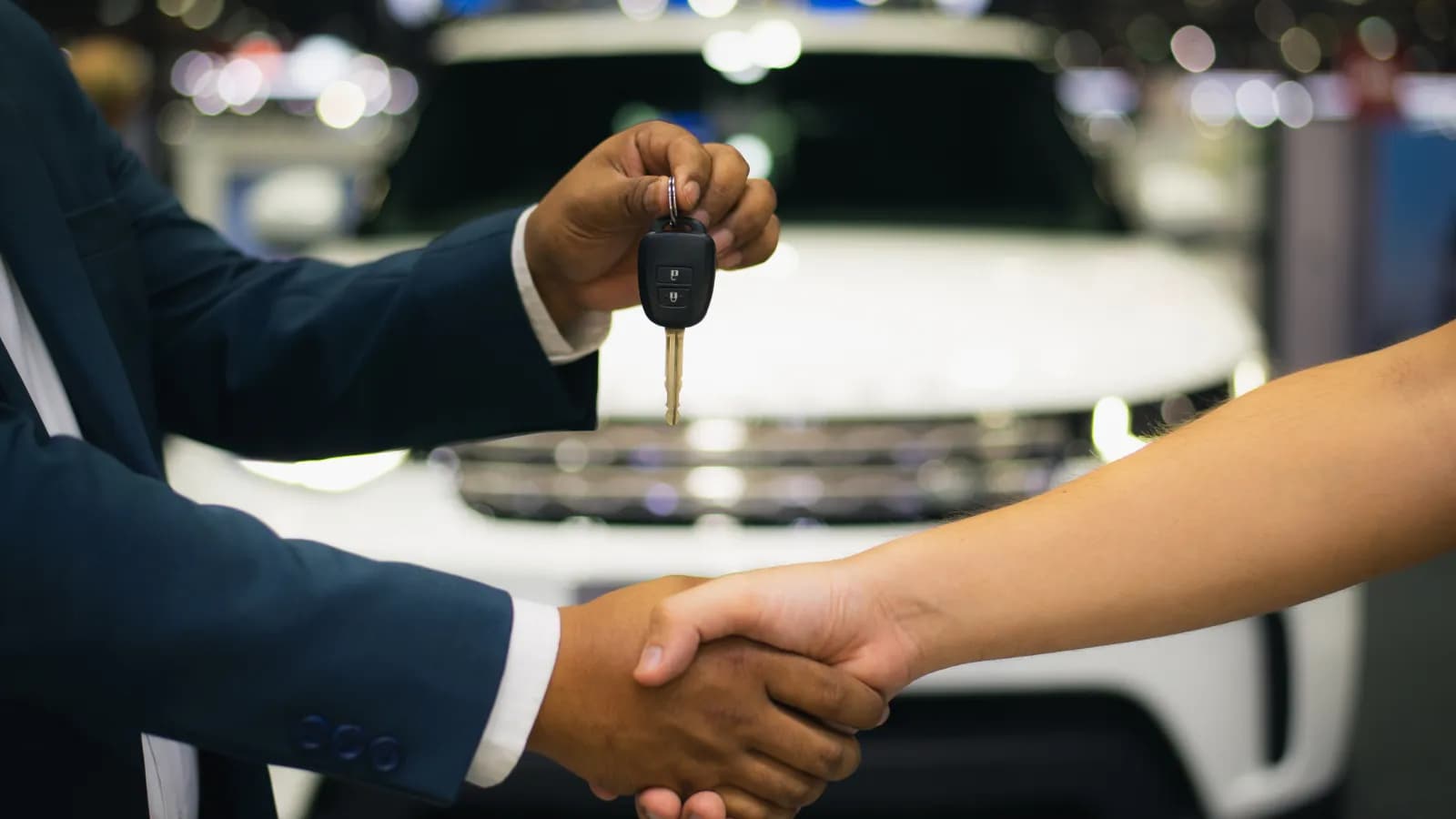 Selling a car safely: spotting cash-for-cars scams before the handshake A buyer handing over car keys during a handshake in front of a white SUV