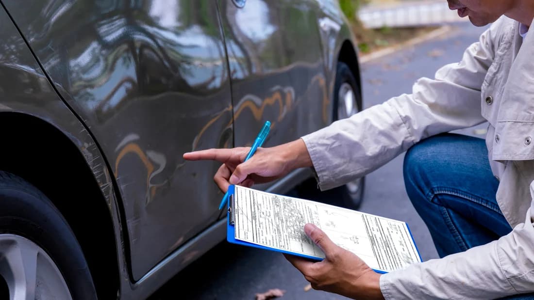 An adjuster valuing a totaled car in Nevada: the payout comes from comparable cars An insurance adjuster writing on a clipboard beside a damaged car: how a totaled car payout in Nevada is valued